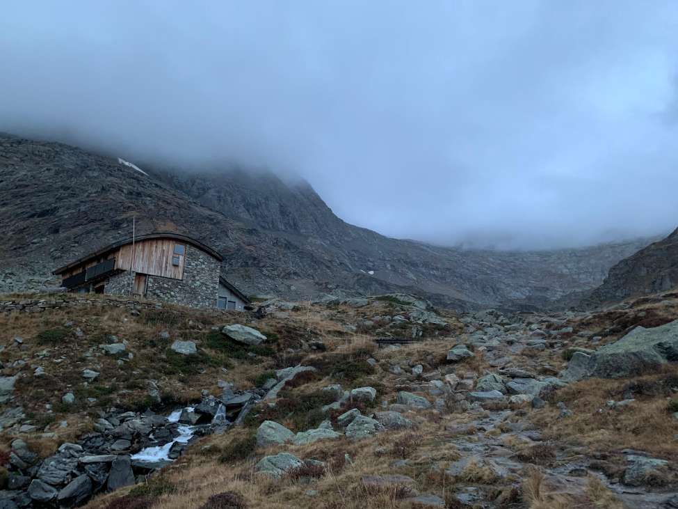 Aussois dağ evi, yanındaki akarsu ve sisli dağlar.